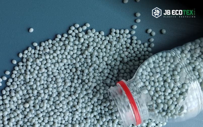 Plastic resin pellets scattered with recycled PET bottle representing sustainable plastic recycling by JB Ecotex